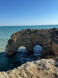 A natural double rock arch in the golden cliffs of the Algarve coast in Portugal, waves washing through it