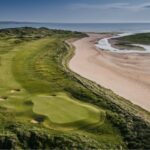 A links green beside a wide sandy shore in Ireland