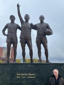 JP Cone in front of the United Trinity statue of George Best, Denis Law and Bobby Charlton at Old Trafford