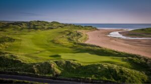 A links green with dunes and a sandy bay behind it in Ireland