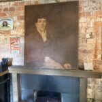 A portrait above the fireplace surrounded by vintage Irish whiskey signs
