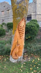 A tree carved with a fox and grapes in wine country near Laguardia