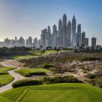 A golf course in Dubai with lush fairways in the desert and the Marina skyline rising behind