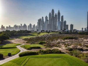 A golf course in Dubai with lush fairways in the desert and the Marina skyline rising behind