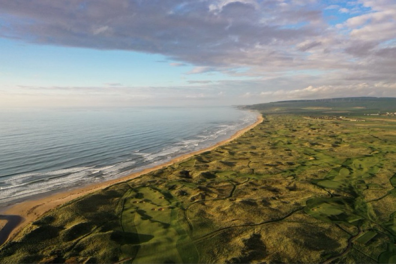 Aerial view at dawn of a links golf course running alongside a sandy beach and dunes on Ireland's Wild Atlantic Way, with the Atlantic Ocean stretching to the horizon