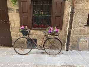A vintage bicycle with flower baskets outside a stone house in Laguardia, Spain