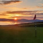 A links green at sunset with a red flag, Ireland