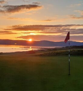 A links green at sunset with a red flag, Ireland