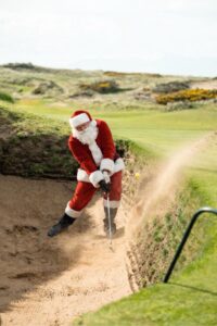 Santa Claus playing out of a bunker on an English links course