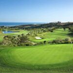 An immaculate green on a Spanish golf course with fairways, a lake and the Mediterranean Sea behind
