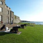 The castle clubhouse at Ardglass Golf Club in County Down, old cannons on the lawn above the sea and golf bags by the door