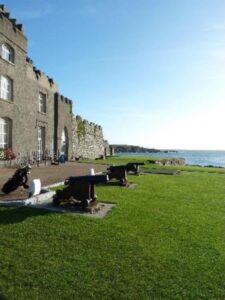 The castle clubhouse at Ardglass Golf Club in County Down, old cannons on the lawn above the sea and golf bags by the door