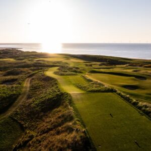 An aerial view of an English links at sunset with the Irish Sea beyond