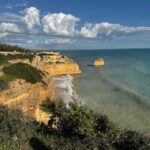 Golden limestone cliffs and a lone sea stack on the Algarve coast in Portugal under a dramatic sky