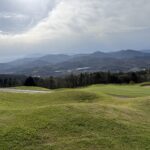A golf course beneath layered mountain ridges in northern Spain