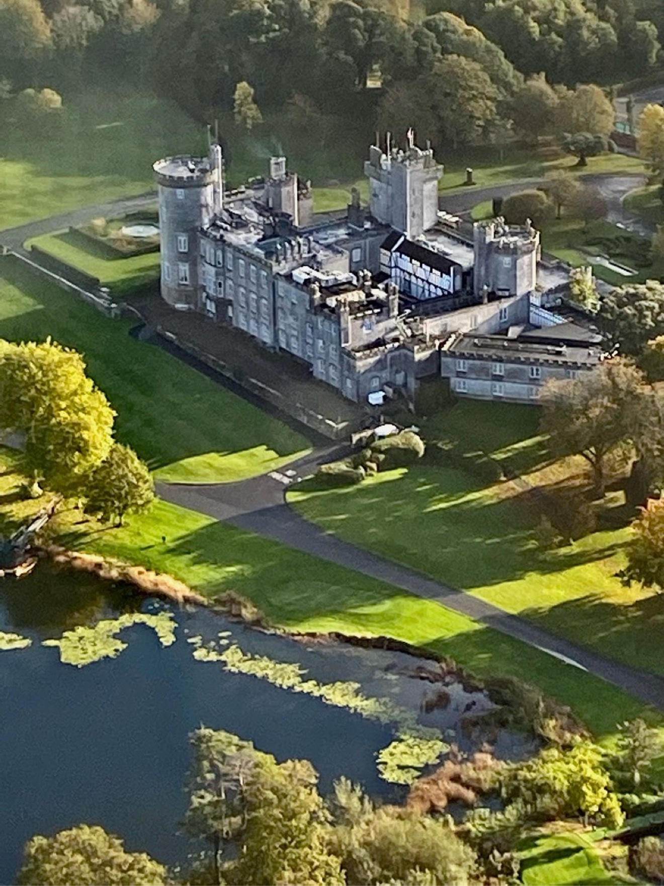 Aerial view of a grey stone castle with round towers beside a lake