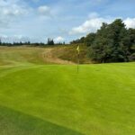 Scottish links golf course fairway with bunker and yellow flagstick