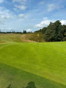 Scottish links golf course fairway with bunker and yellow flagstick