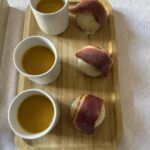 Cups of salmorejo and jamón-topped bread on a tasting board in Spain