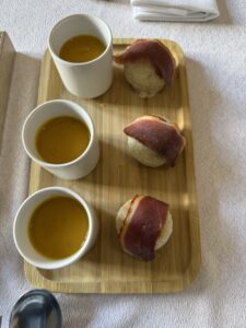 Cups of salmorejo and jamón-topped bread on a tasting board in Spain