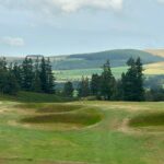 Rolling Scottish golf landscape with forested hills