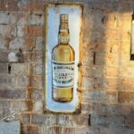 A vintage John Jameson & Son Dublin whiskey sign on a brick wall