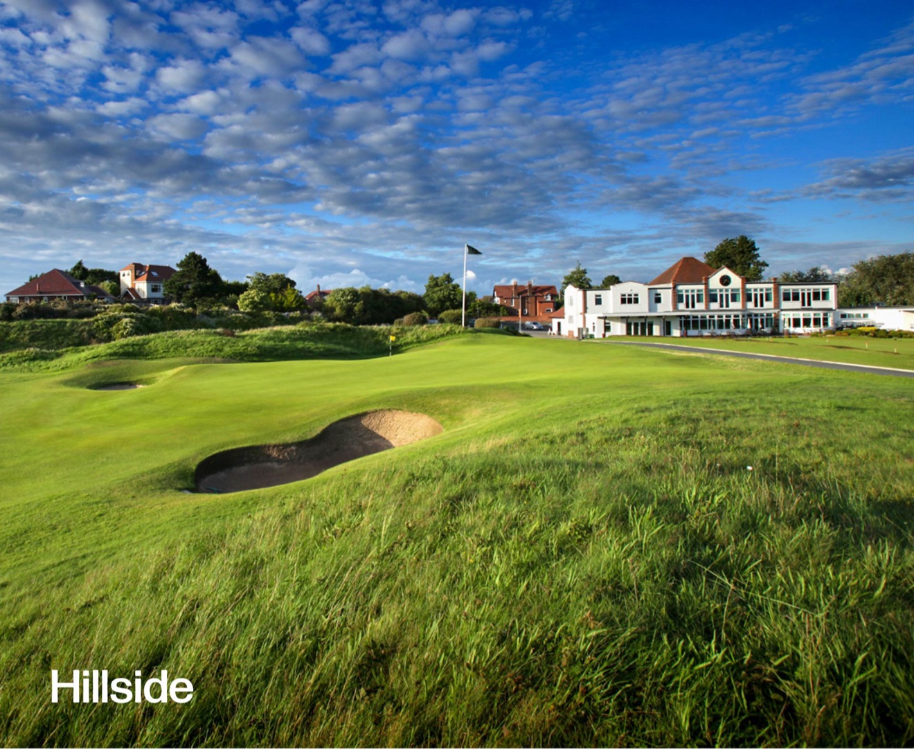 the Old Course at St Andrews at sunset with the town buildings behind a white fence