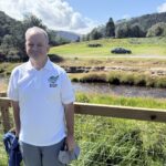 JP of EGT in his EGT polo at Glendalough, the river and the round tower behind him