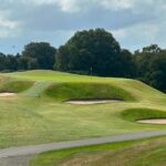 Scotland golf green with yellow flagstick surrounded by trees