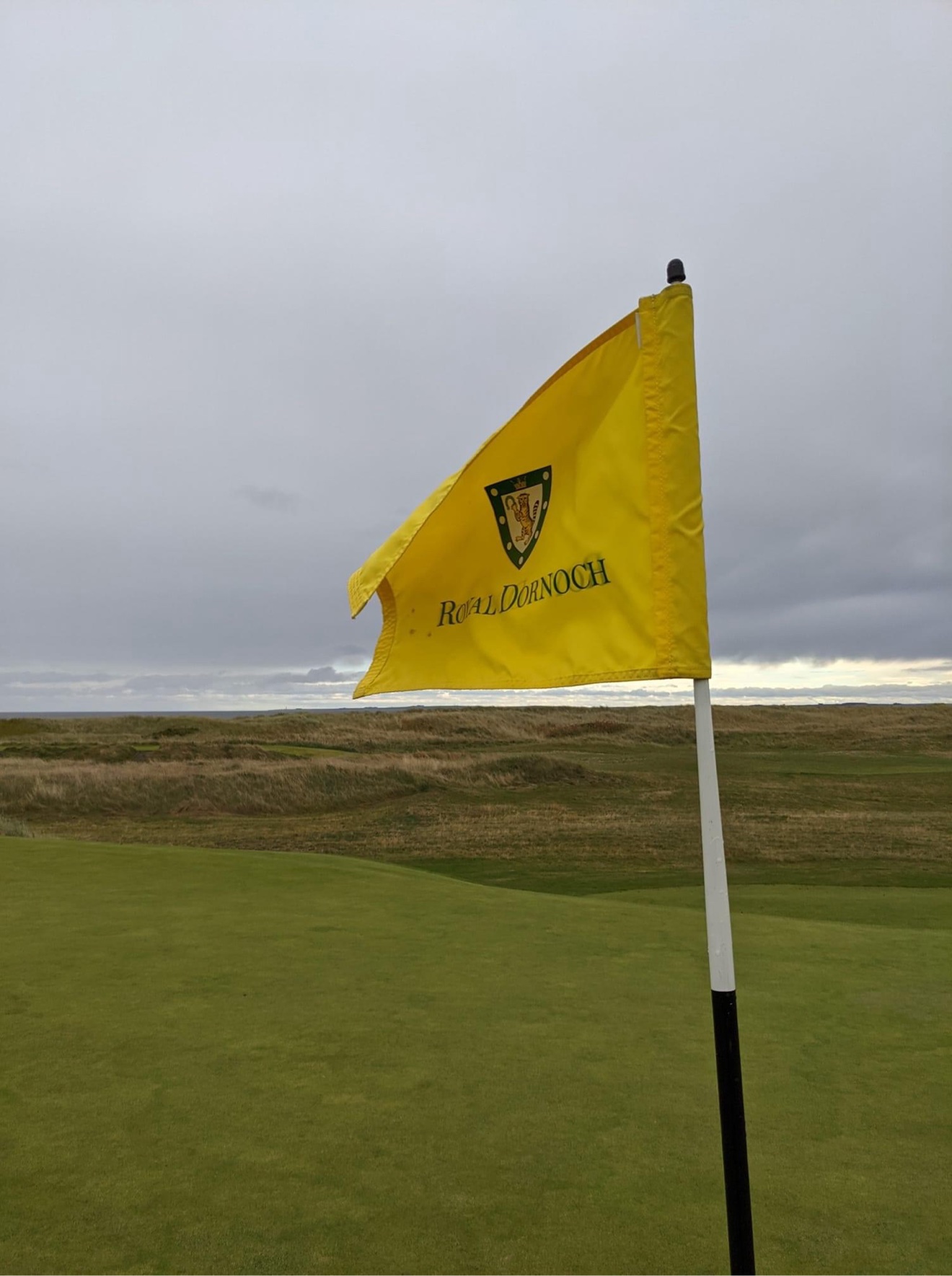 Yellow flagstick reading Royal Dornoch on a links course