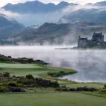 A golf course beside a Highland loch with a castle on the far shore