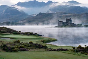 A golf course beside a Highland loch with a castle on the far shore