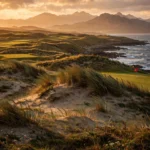 A links golf green beside the sea in Wales at golden hour, dunes and mountains behind