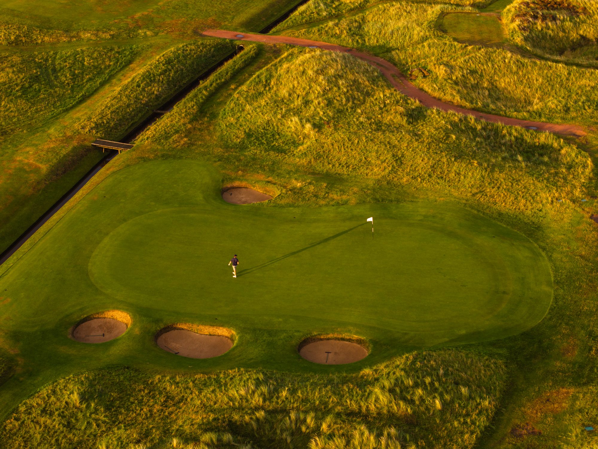 Golden hour on a Western Gailes green, ringed by pot bunkers and dunes, Ayrshire